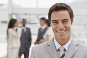 Portrait of happy young businessman with colleagues in the background